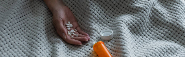 cropped view of depressed woman with climax holding pills in hand, banner