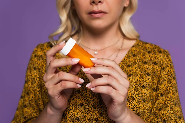 cropped view of blonde woman with menopause holding bottle with pills isolated on purple