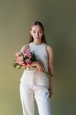 stylish woman in white clothes posing with bouquet of alstroemeria isolated on green