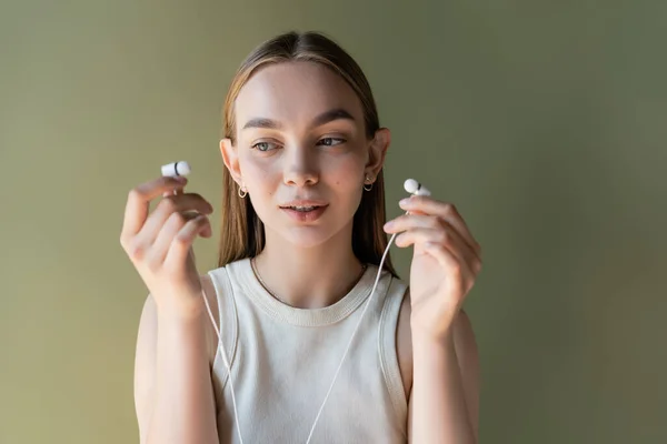 Young Woman White Tank Top Holding Wired Earphones Isolated Green — ストック写真