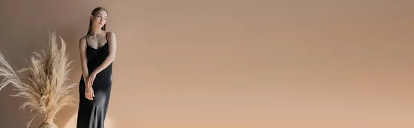 Молода Жінка Чорній Сукні Ремінця Позує Біля Сушених Колосків Бежевому — стокове фото