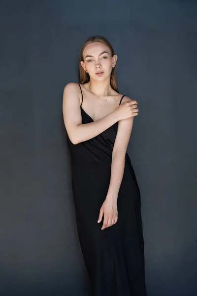Young Woman Black Strap Dress Looking Camera Dark Background — Zdjęcie stockowe