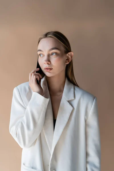 Young Woman White Blazer Looking Away While Talking Smartphone Isolated — Fotografia de Stock