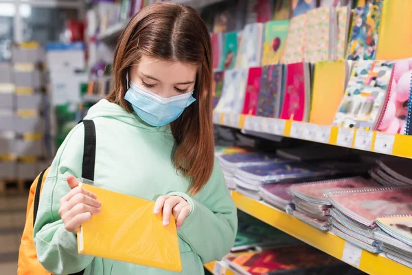 Child Medical Mask Holding Notebook While Choosing School Supplies Shop — Fotografia de Stock