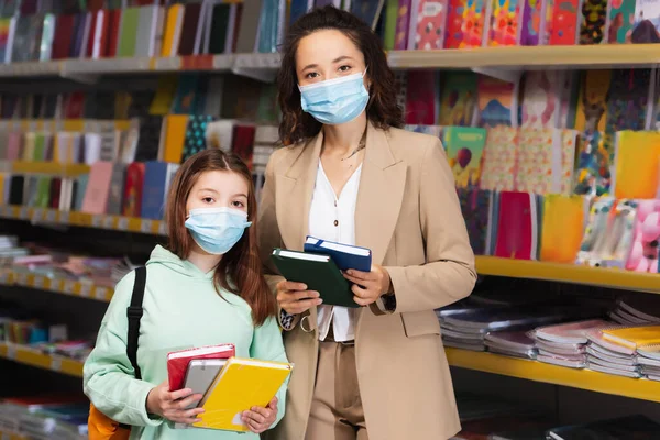 Mother Child Medical Masks Holding Colorful Notebooks Stationery Store — стоковое фото