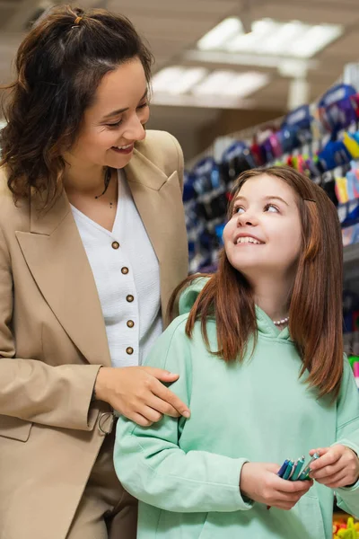 Cheerful Woman Looking Happy Daughter Holding New Pens Stationery Shop — Foto Stock