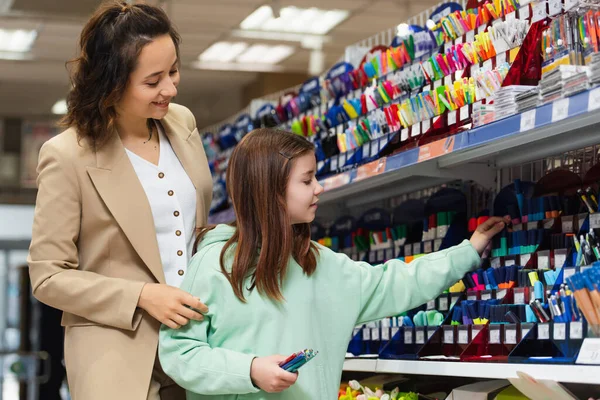 Schoolgirl Holding Pens Smiling Mom Rack Stationery Store — 图库照片