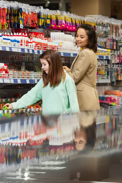 Schoolgirl Smiling Mother Choosing New Stationery Store — стоковое фото