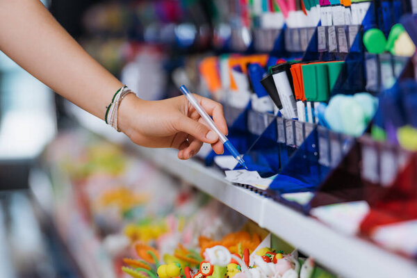 partial view of student in beaded bracelets trying ball pen in stationery shop