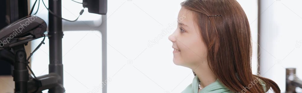 side view of smiling girl looking at payment terminal in shop, banner