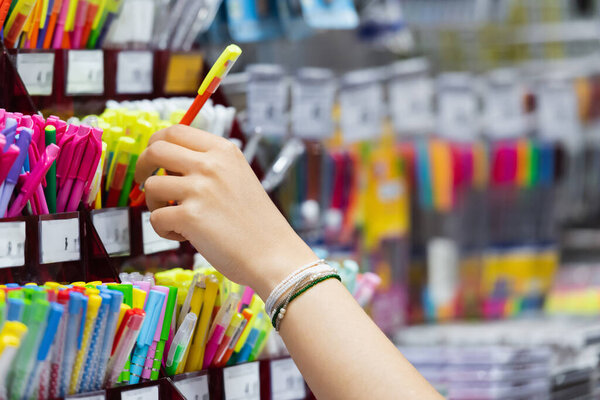 partial view of woman in beaded bracelets near colorful pencils in stationery shop