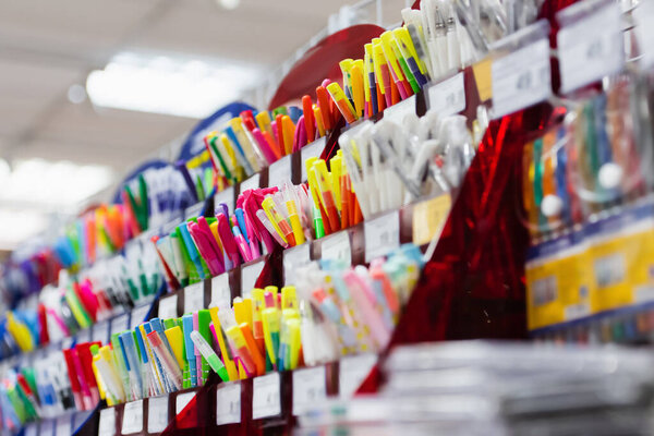 rack with different multicolored pens in stationery store