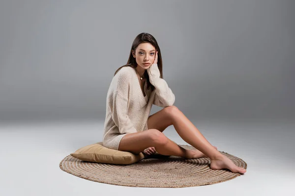 Young Woman Bare Legs Sitting Carpet Pillow Grey Background — Φωτογραφία Αρχείου