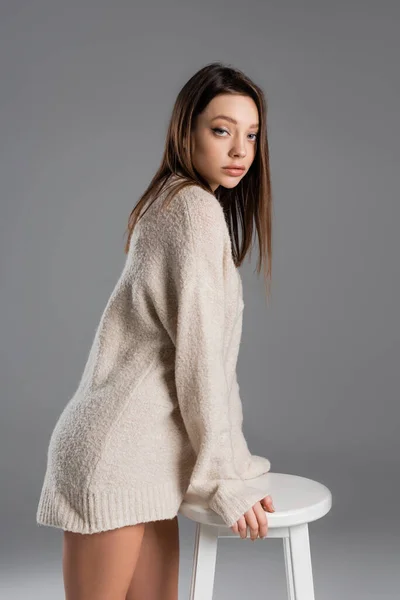 Brunette Woman Cozy Sweater Posing Stool Looking Camera Grey Background — Stock Photo, Image
