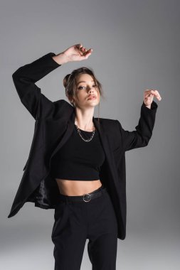 young and sensual woman in black trendy clothes posing isolated on grey