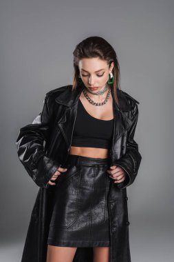 fashionable woman in black crop top and leather clothing isolated on grey