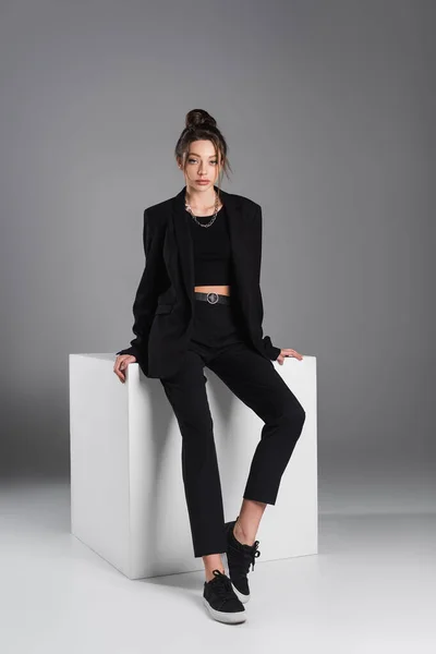 Full Length Woman Black Sneakers Suit Sitting White Cube Grey — Stockfoto