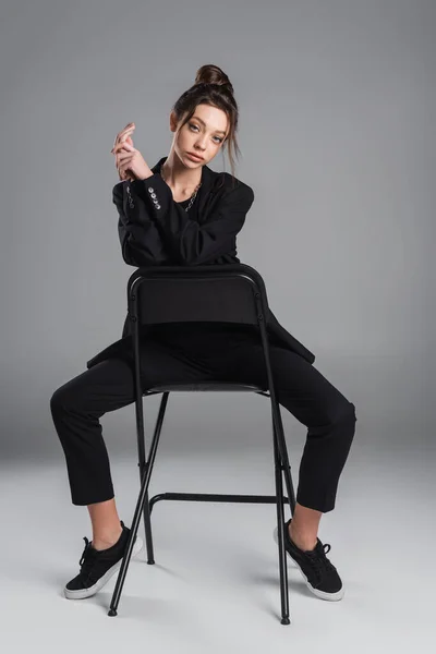 Full Length Pretty Woman Black Suit Sneakers Posing Chair Grey — Fotografia de Stock