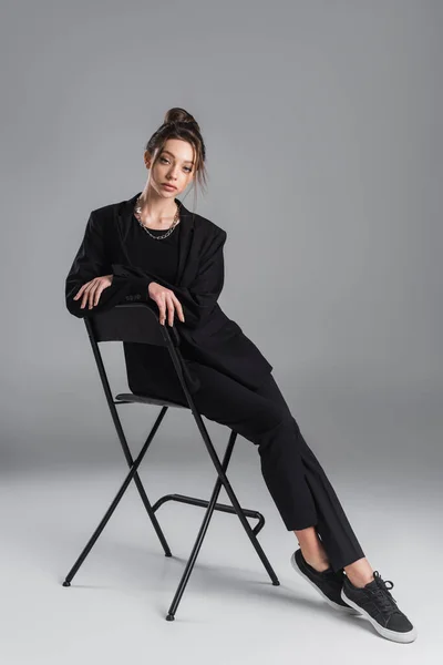 Full Length Woman Black Stylish Suit Sneakers Posing Stool Grey — стоковое фото