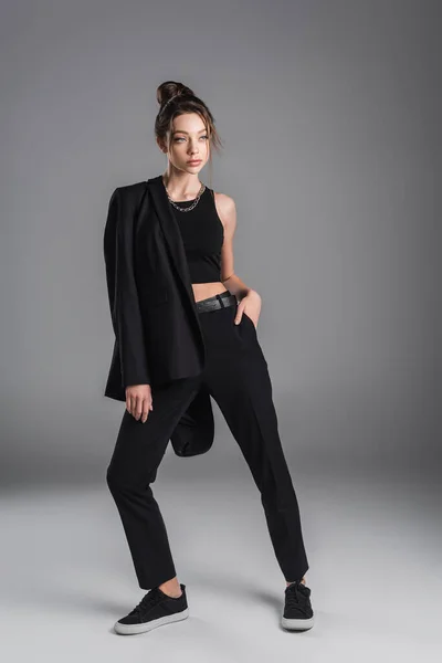 Повнометражна Модна Жінка Позує Чорною Курткою Рукою Кишені Сірому Фоні — стокове фото