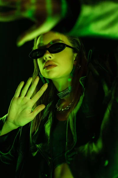 Young Woman Dark Sunglasses Gesturing Green Neon Light Isolated Black — Foto Stock