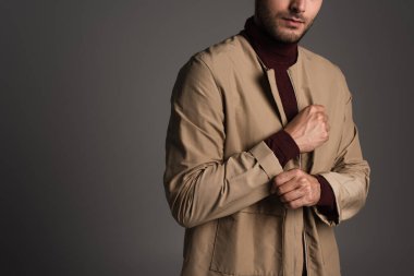 Cropped view of man adjusting sleeve of autumn jacket isolated on grey 