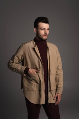 Bearded man posing in autumn jacket isolated on grey 