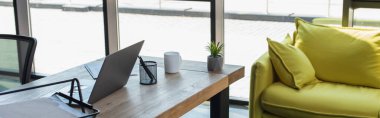 Laptop and coffee cup on working table in office, banner 