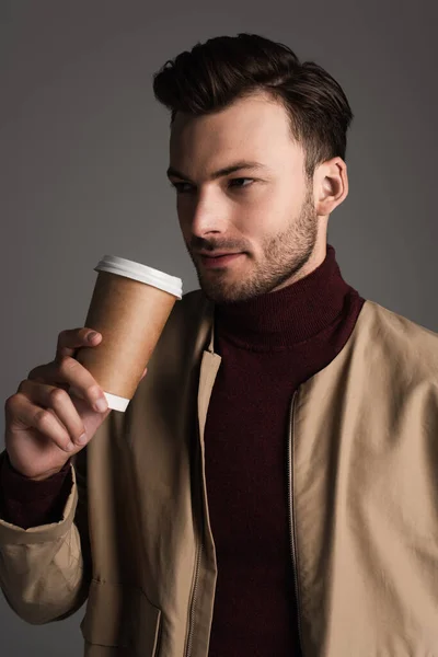 Stylish man in autumn outfit holding takeaway drink isolated on grey