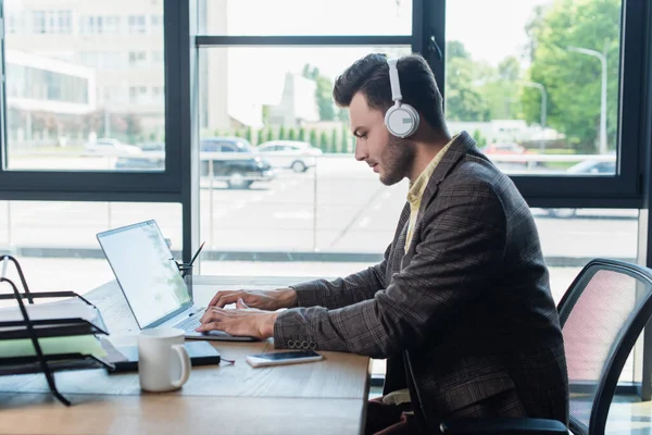 Side View Young Businessman Headphones Using Laptop Paperwork Cup Office — Stok fotoğraf