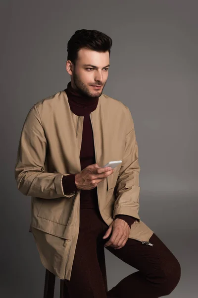 Stylish Man Autumn Outfit Holding Smartphone While Sitting Chair Isolated — 스톡 사진