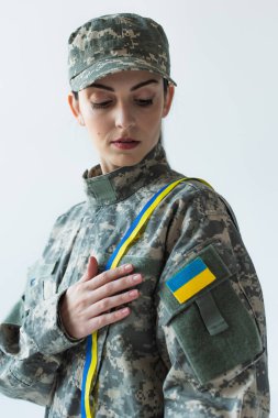 Portrait of soldier with ukrainian flag on uniform and blue and yellow ribbon isolated on grey 