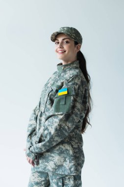 Gri üzerinde Ukrayna bayrağı bulunan şapkalı ve üniformalı pozitif asker. 