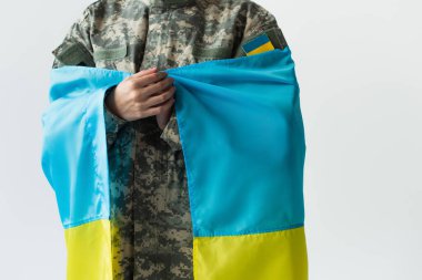 Cropped view of servicewoman holding blue and yellow ukrainian flag isolated on grey 