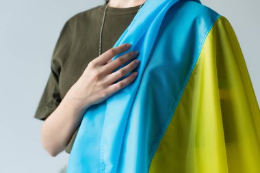 Cropped view of servicewoman holding ukrainian flag isolated on grey 