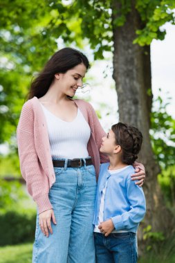 smiling woman and girl looking at each other in park