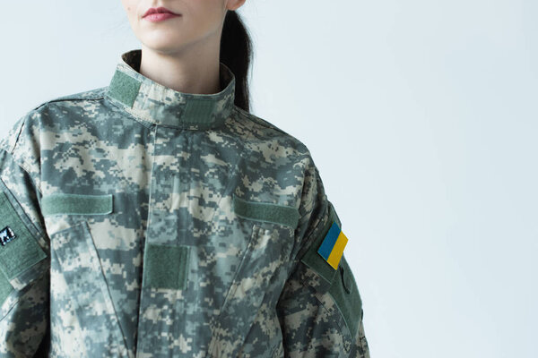 Cropped view of woman in military uniform with chevron of ukrainian flag isolated on grey 
