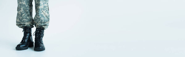 Cropped view of soldier in uniform and boots on grey background, banner 