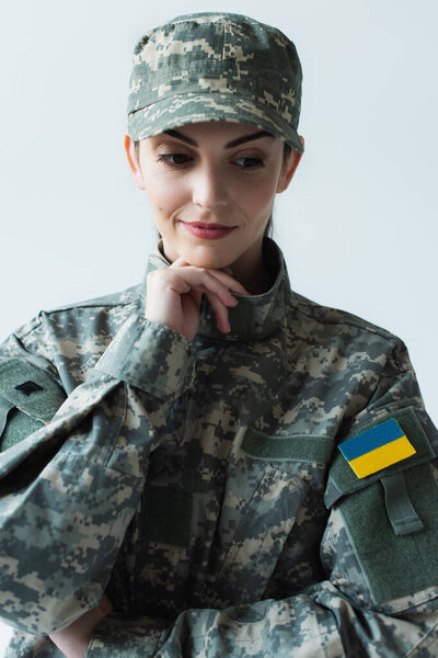 Portrait of pensive soldier in uniform with ukrainian flag isolated on grey 