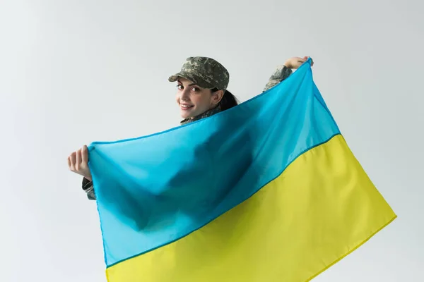 Усміхнений Солдат Дивиться Камеру Тримаючи Прапор Українки Ізольованим Сірому — стокове фото