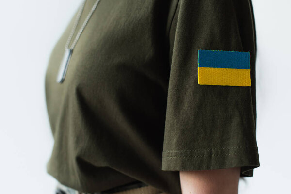 Cropped view of ukrainian flag on chevron of blurred soldier isolated on grey 