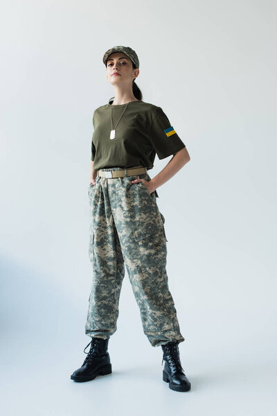 Soldier with ukrainian flag on chevron posing on grey background