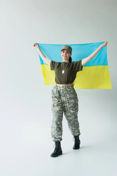 Smiling Soldier Uniform Cap Holding Ukrainian Flag While Walking Grey — стоковое фото