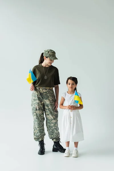 Gri Arka Planda Kızının Yanında Ukrayna Bayrağı Tutan Asker — Stok fotoğraf
