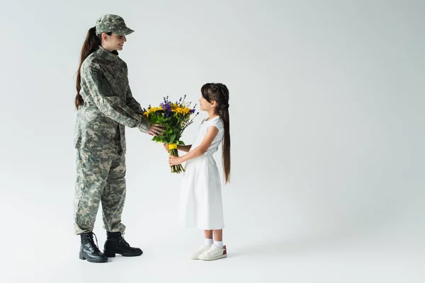 Side View Child Giving Blue Yellow Flowers Soldier Grey Background — стоковое фото