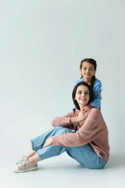 Girl Embracing Happy Mother Looking Camera While Sitting Grey Background — 图库照片