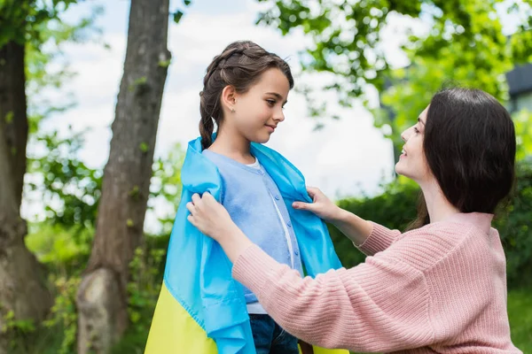 Smiling Woman Looking Daughter Covering Her Ukrainian Flag Park — стоковое фото