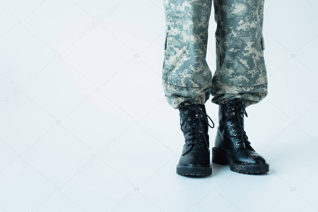 Cropped view of soldier in boots standing on grey background