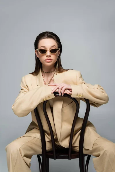 Brunette Woman Stylish Beige Outfit Trendy Sunglasses Sitting Wooden Chair — Foto de Stock