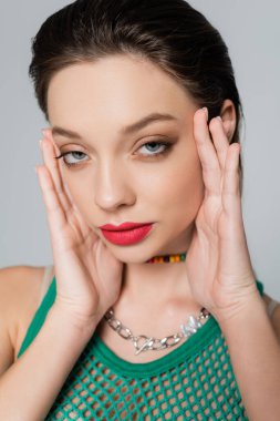close up of stylish woman with red lips looking at camera while posing isolated on grey